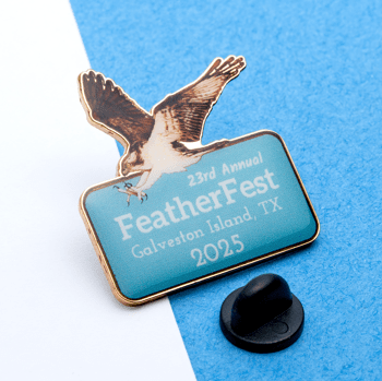 Custom lapel pin featuring an osprey in flight above a light blue rectangle with FeatherFest 2025 Galveston Island, TX text.