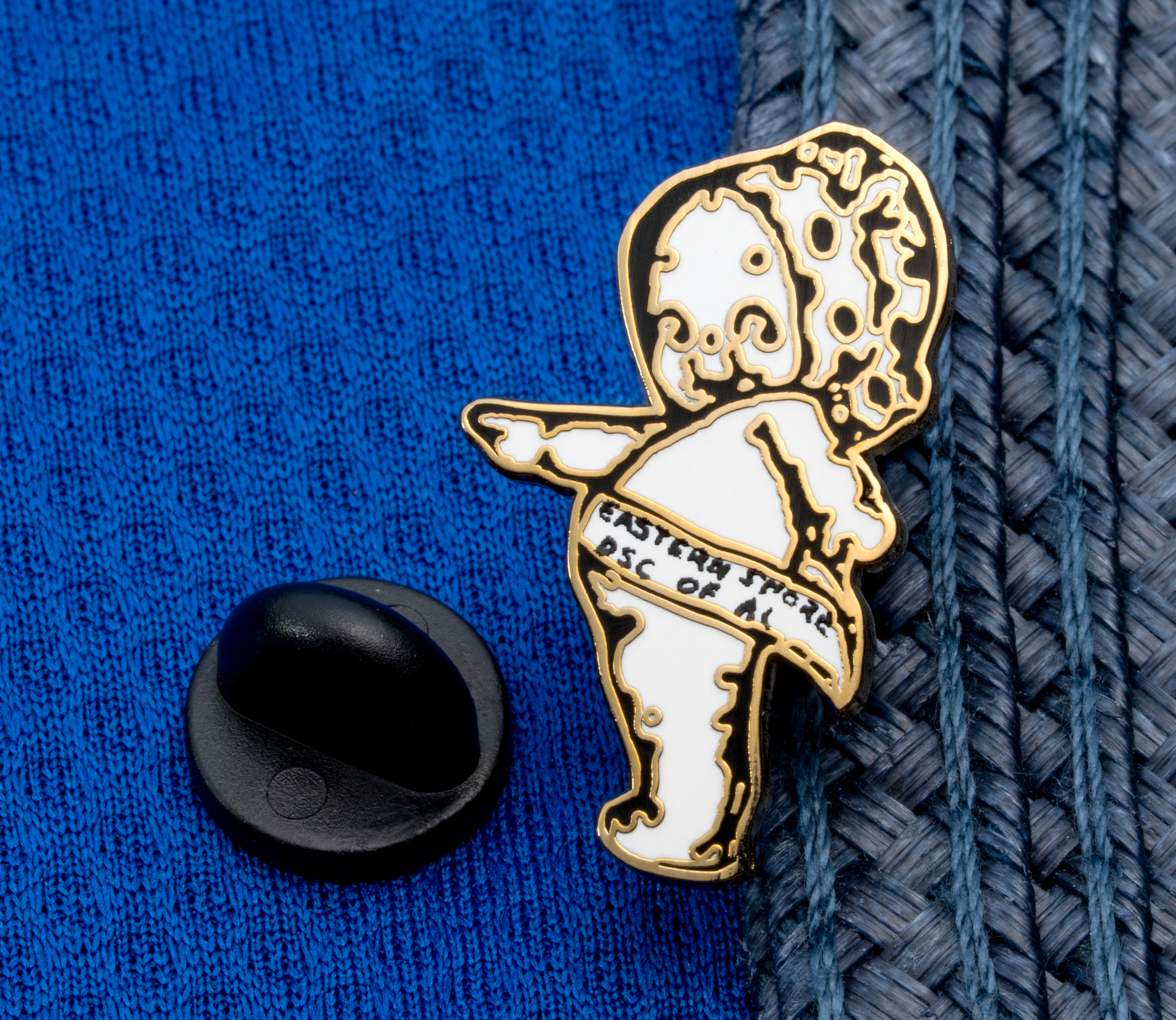 map[name:Gold and white enamel lapel pin of a Kewpie doll figure with 'Eastern Shore DSC of AL' text on a banner, displayed on a blue fabric and straw hat background. naturalSort:Gold and white enamel lapel pin of a Kewpie doll figure with 'Eastern Shore DSC of AL' text on a banner, displayed on a blue fabric and straw hat background.]