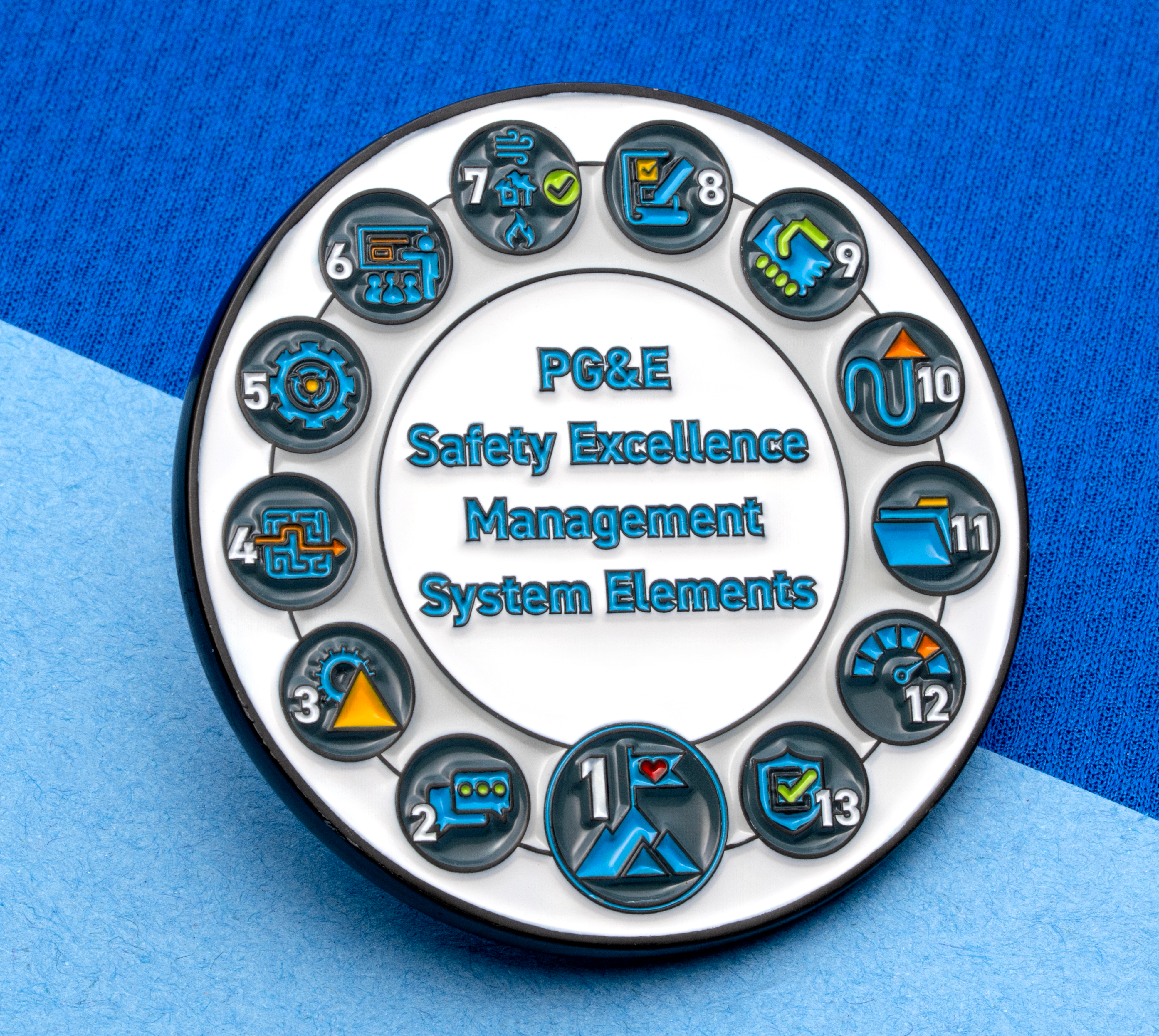 map[name:Circular custom enamel pin for PG&E Safety Excellence Management System Elements featuring thirteen numbered icons arranged in a ring on a white background. naturalSort:Circular custom enamel pin for PG&E Safety Excellence Management System Elements featuring thirteen numbered icons arranged in a ring on a white background.]