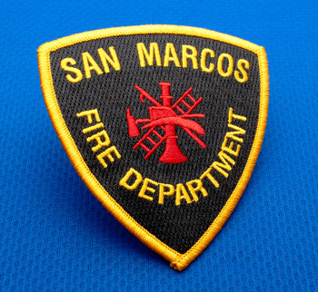 Shield-shaped embroidered patch for San Marcos Fire Department featuring a red scramble icon on a black background with a gold border.