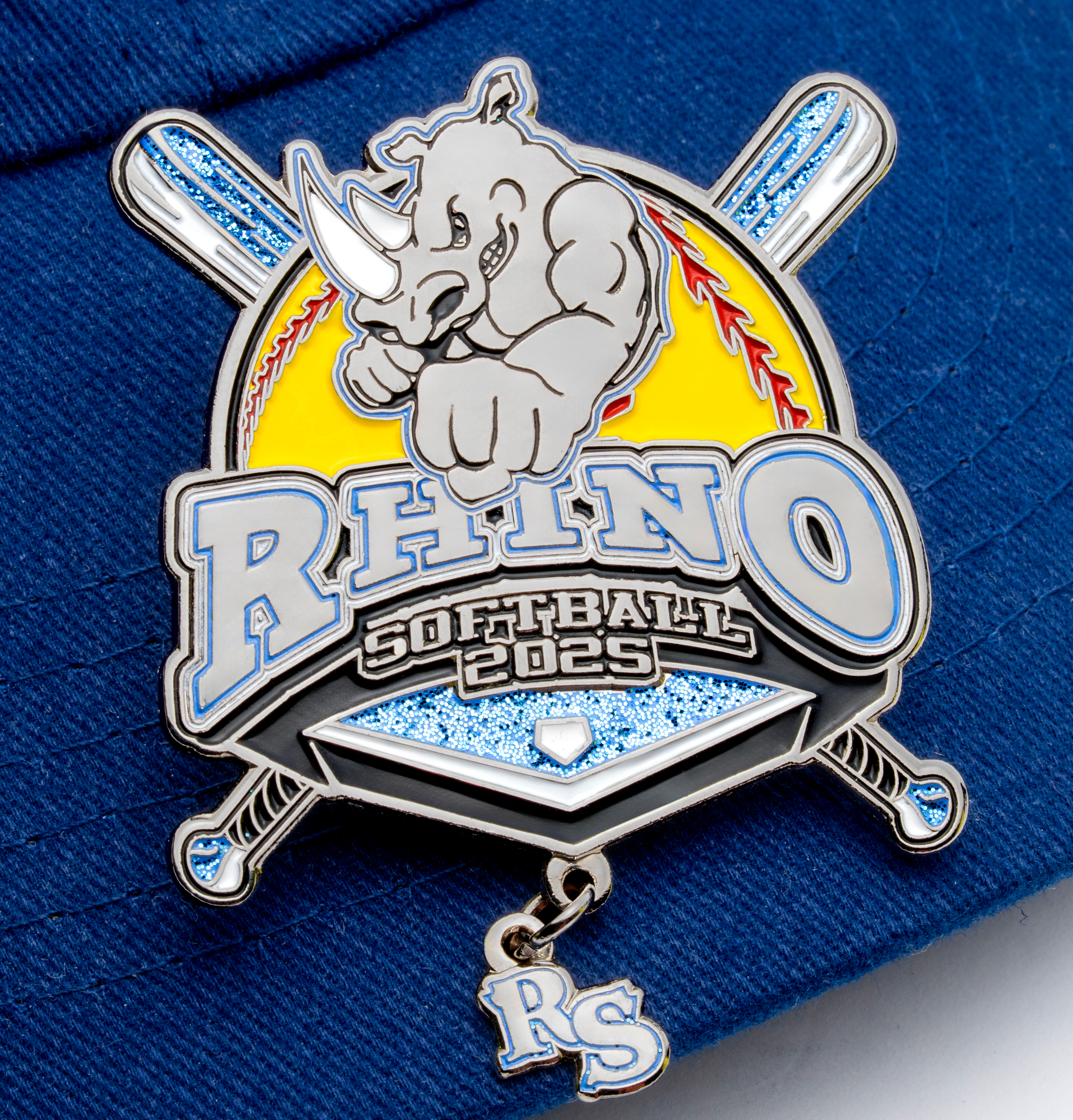 map[name:Enamel rhino softball trading pin with crossed bats, glitter accents, and a dangling RS charm on a blue cap. naturalSort:Enamel rhino softball trading pin with crossed bats, glitter accents, and a dangling RS charm on a blue cap.]
