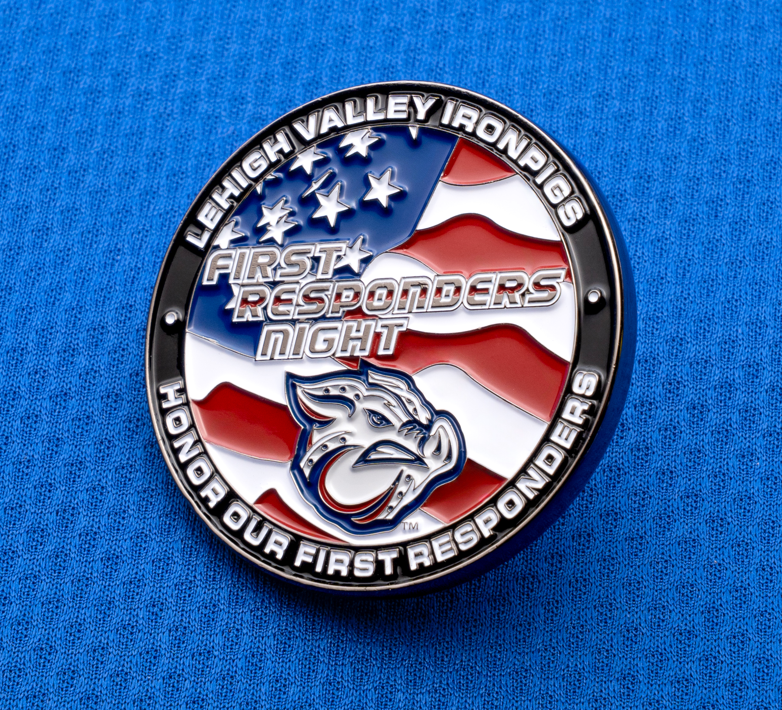 Round enamel lapel pin with an American flag background, IronPigs logo, and text reading First Responders Night on a blue textured surface.