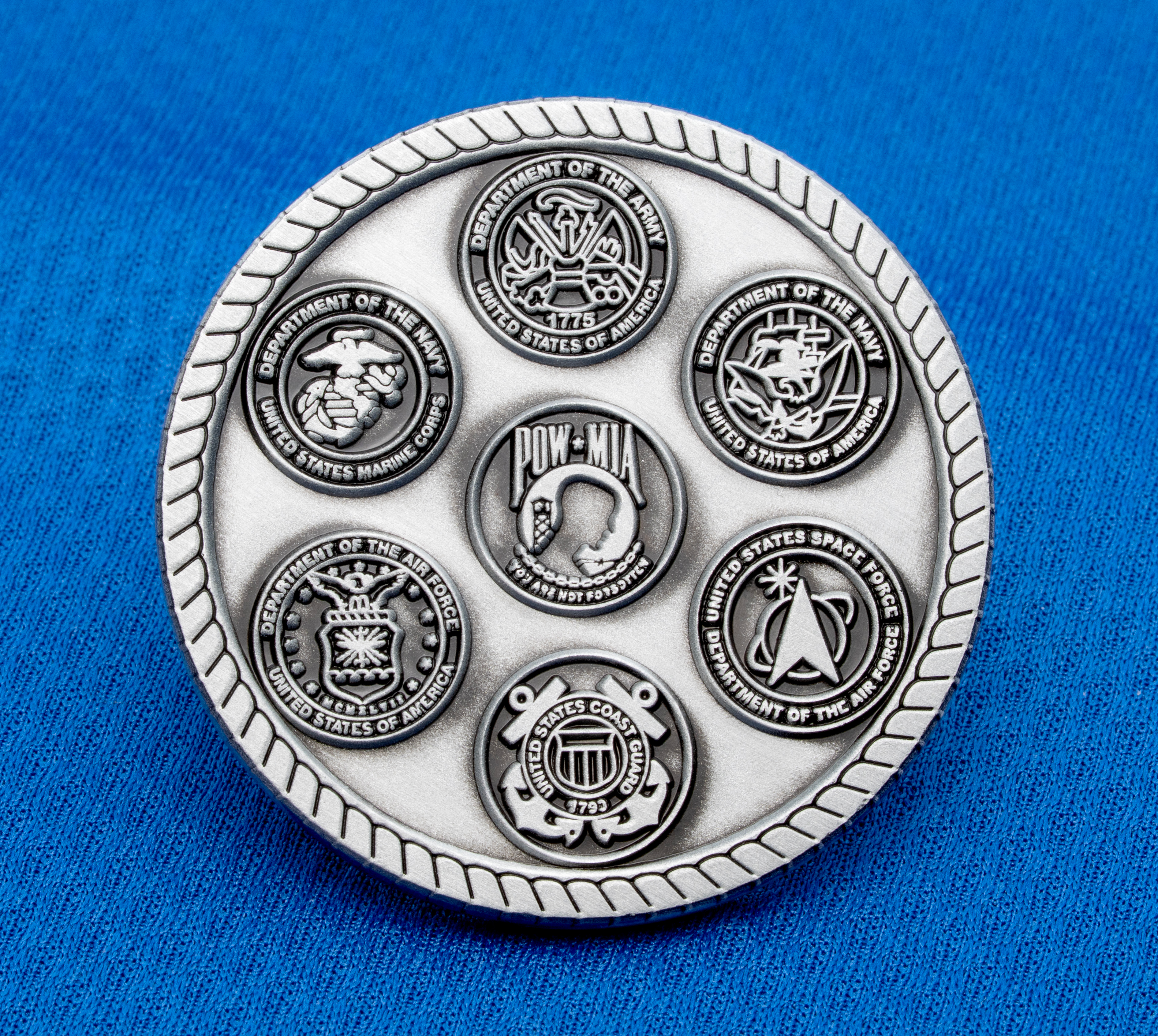 map[name:Antiqued silver medallion featuring emblems of the Army, Navy, Air Force, Marine Corps, Coast Guard, Space Force, and POW-MIA on a blue background. naturalSort:Antiqued silver medallion featuring emblems of the Army, Navy, Air Force, Marine Corps, Coast Guard, Space Force, and POW-MIA on a blue background.]