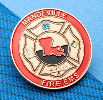 Circular gold lapel pin with a red border, featuring a Maltese cross, the state of Louisiana, and Mandeville Fire/EMS text.