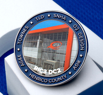 Circular challenge coin featuring an image of a QTS data center building, labeled RIC3 DC2 Henrico County with surrounding partner names.