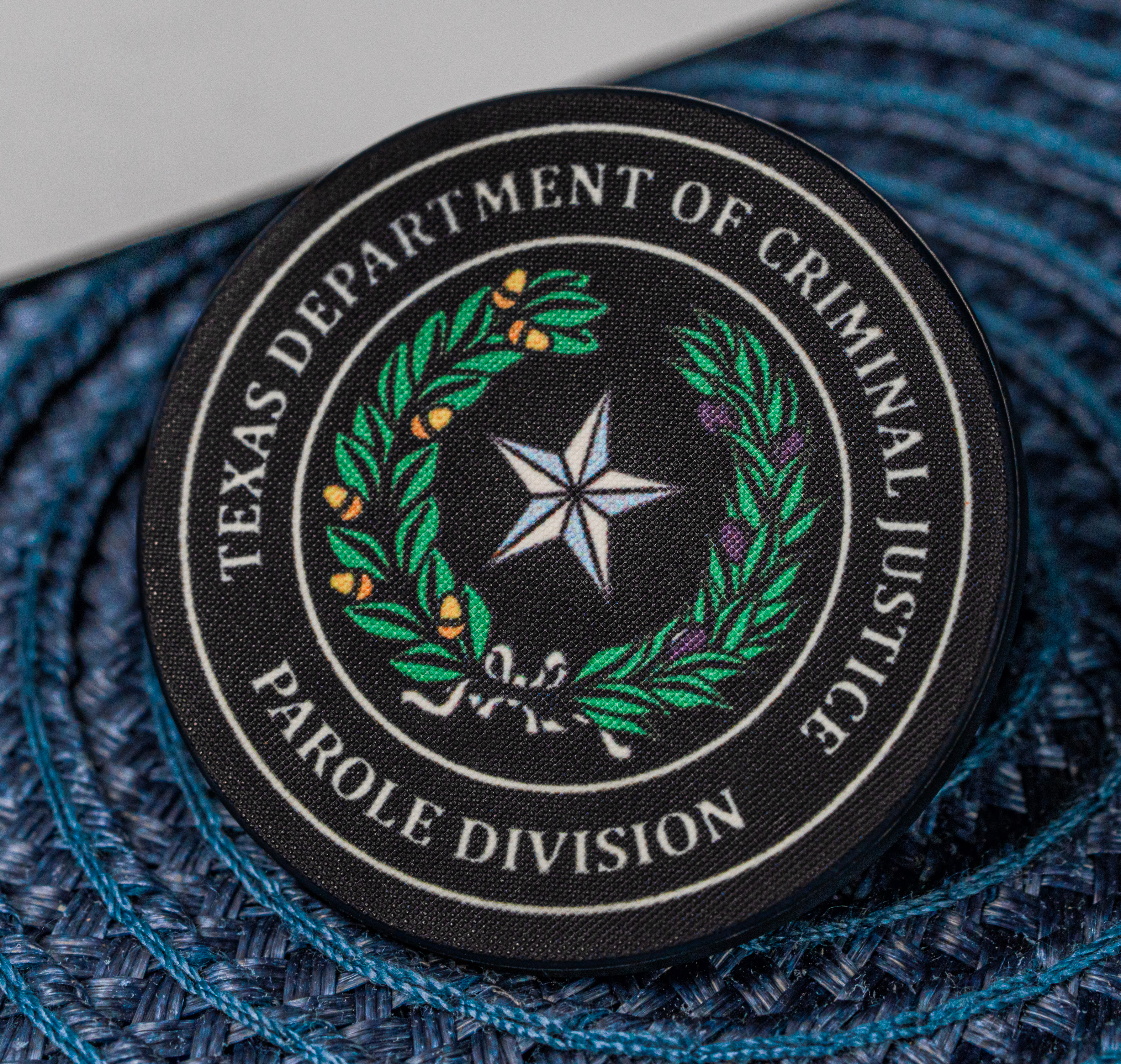 Round black lapel pin for the Texas Department of Criminal Justice Parole Division featuring a lone star and laurel wreath.