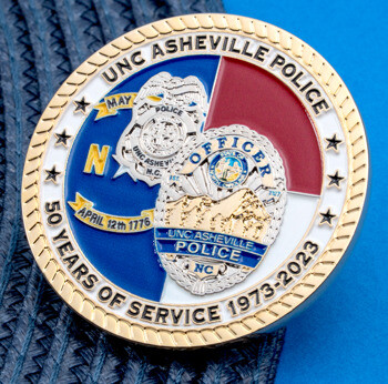 UNC Asheville Police challenge coin with 50 years of service 1973-2023 text, police badge emblems, and gold rope edge.