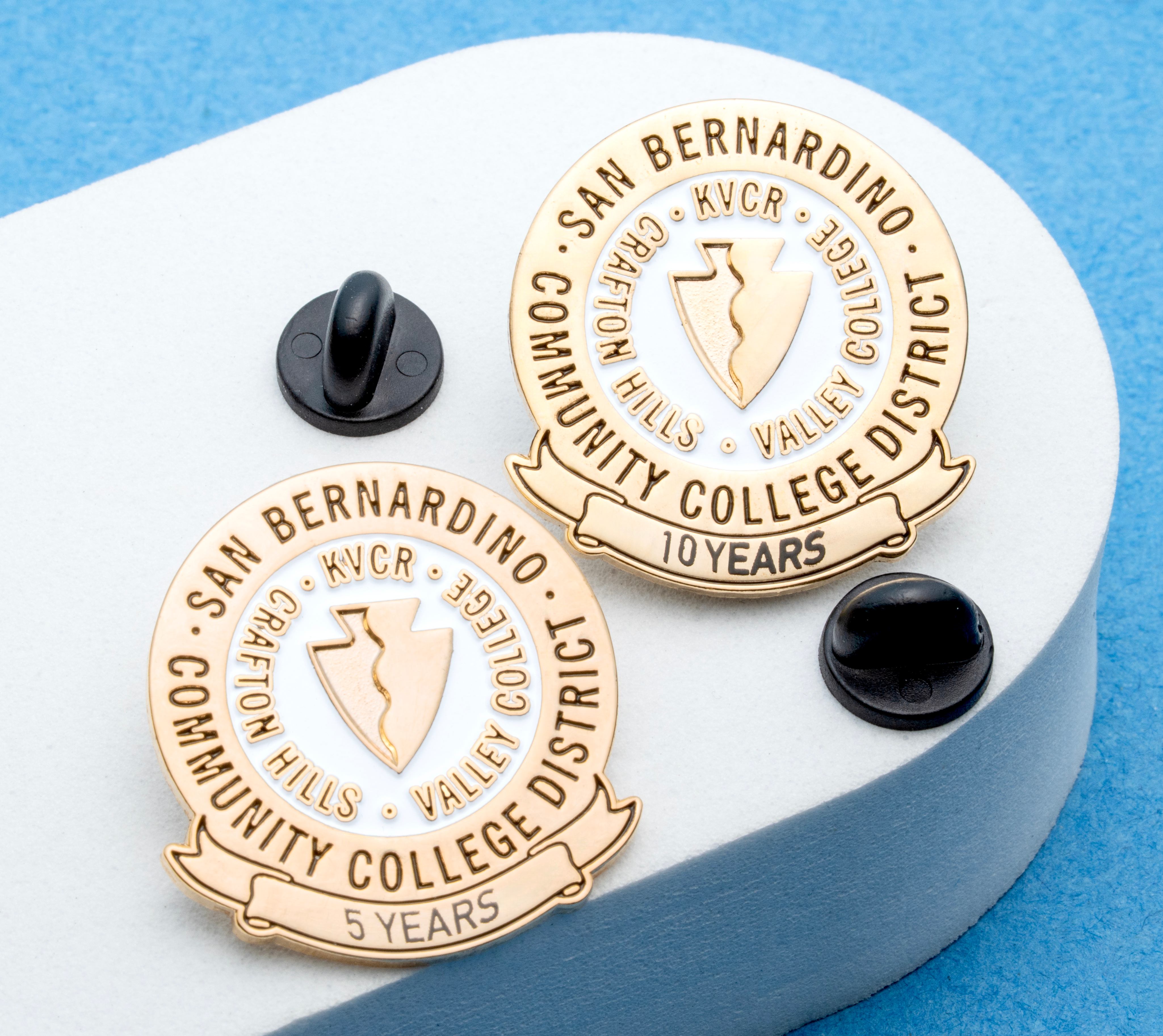 Gold and white lapel pins for San Bernardino Community College District featuring 5 and 10 year service milestones with arrowhead emblems.