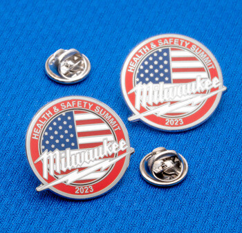 Round lapel pins featuring the American flag, Milwaukee script, and Health and Safety Summit 2023 text on a blue background.