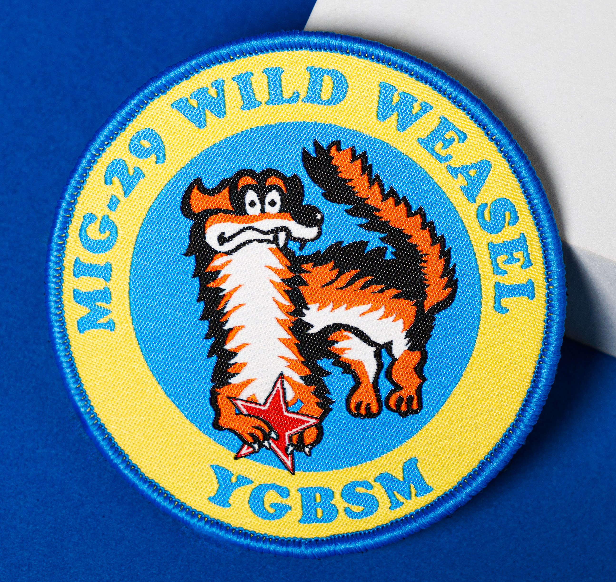 Circular embroidered MiG-29 Wild Weasel patch featuring a cartoon weasel and red star on a blue and yellow background.