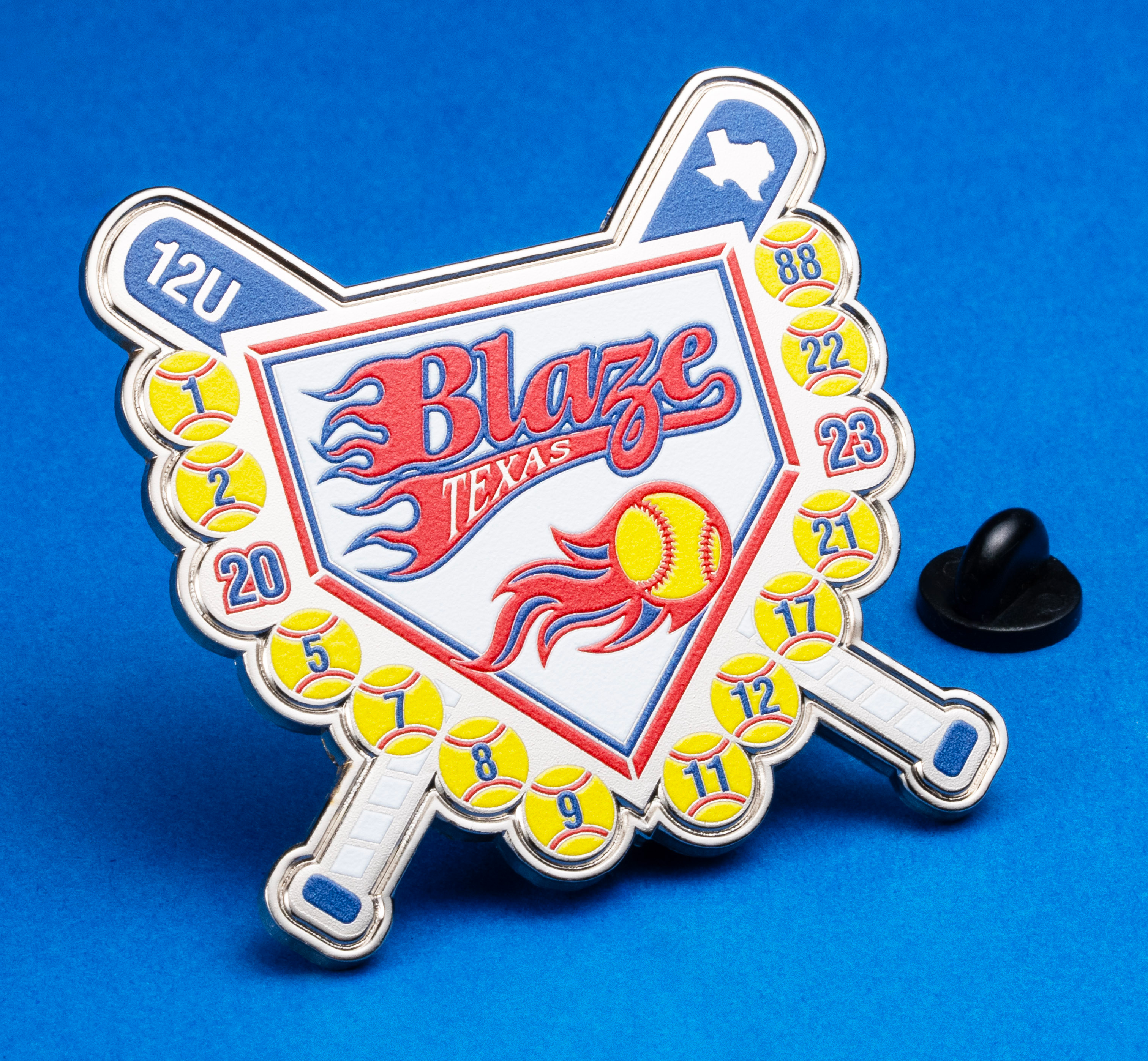 Shield-shaped softball trading lapel pin featuring crossed bats, a flaming softball, and the Texas Blaze logo on a blue background.