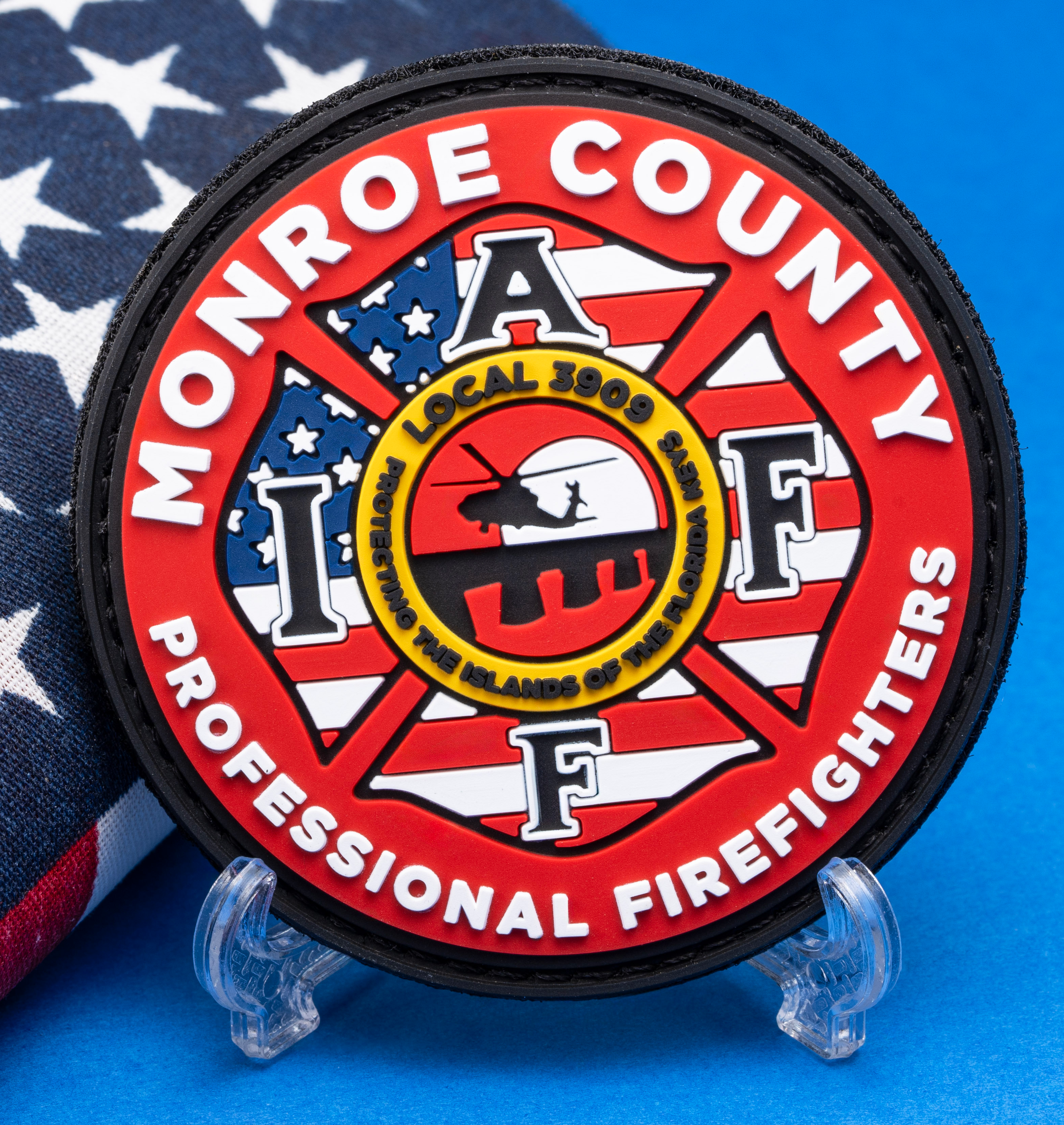 PVC patch for Monroe County IAFF Professional Firefighters Local 3909 featuring a Maltese cross and helicopter sunset icon over an American flag background.