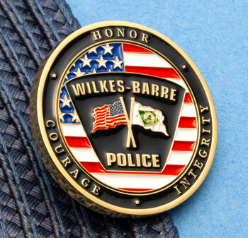 Circular Wilkes-Barre Police challenge coin featuring the American flag and crossed flags design on a gold and black finish.