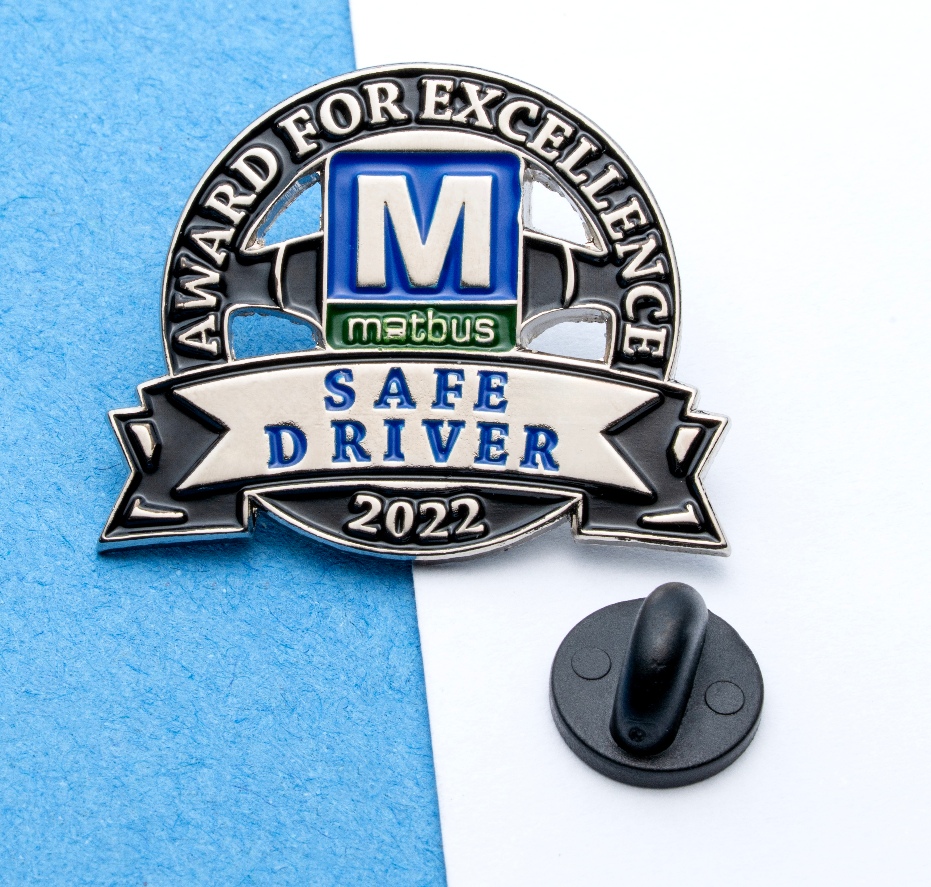 Enamel lapel pin for MATBUS Safe Driver 2022 Award for Excellence with blue and green accents and a black rubber backer.