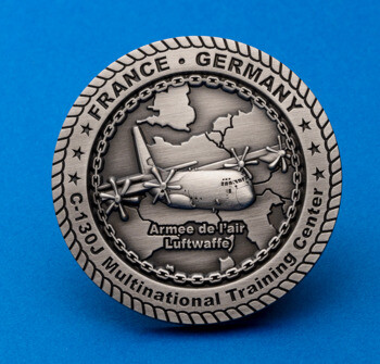 Antiqued silver challenge coin featuring a C-130J aircraft, a map of Europe, and text for France, Germany, and the Multinational Training Center.