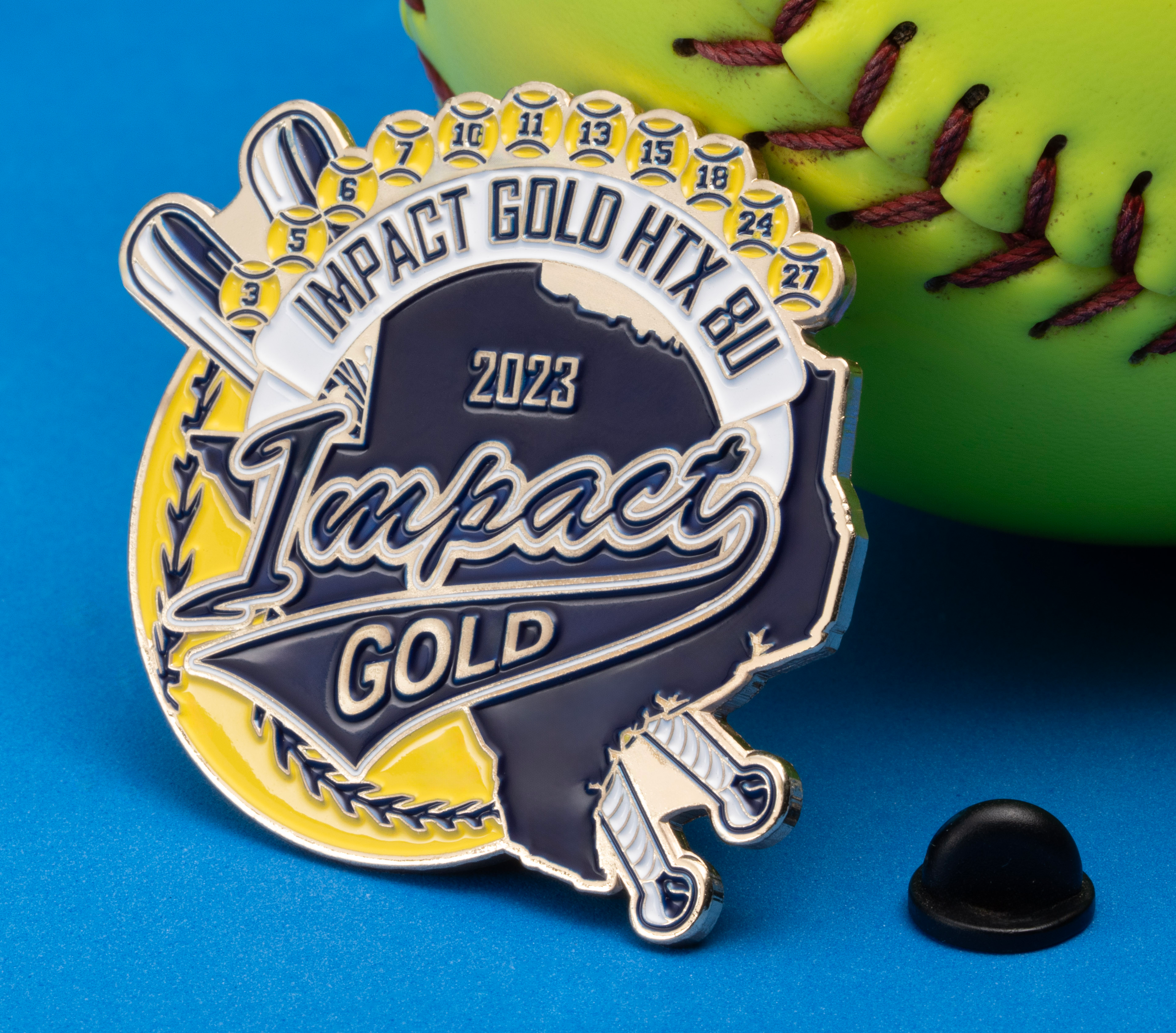 Custom softball lapel pin featuring Impact Gold HTX 8U branding, baseball bats, and a yellow softball background resting against a yellow softball.