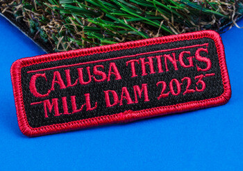 Rectangular embroidered patch with red text reading Calusa Things Mill Dam 2023 on a black background with a red border.