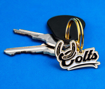 Custom Colts keychain with a horseshoe design and script lettering attached to a gold ring with keys on a blue background.