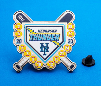 Shield shaped softball trading pin featuring Nebraska Thunder text, crossed bats, lightning bolt, and numbered softballs.