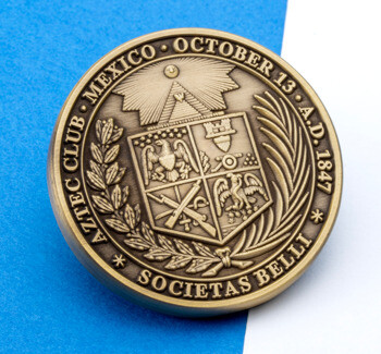 Antiqued bronze round medallion for the Aztec Club of 1847 featuring a central coat of arms and laurel wreath on a blue and white background.