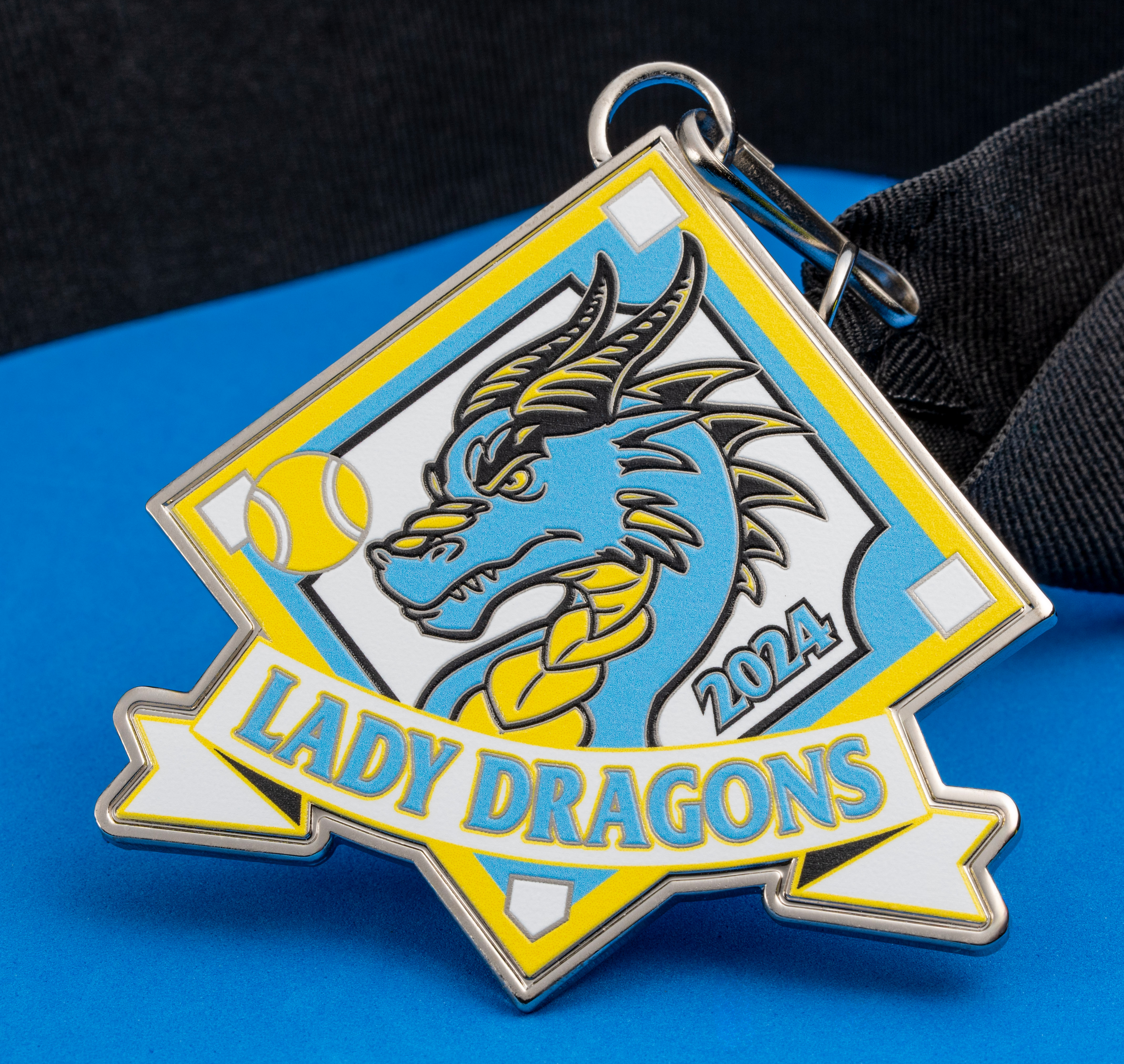 Custom diamond-shaped medal featuring a blue dragon, a yellow softball, and the text Lady Dragons 2024 on a black ribbon.