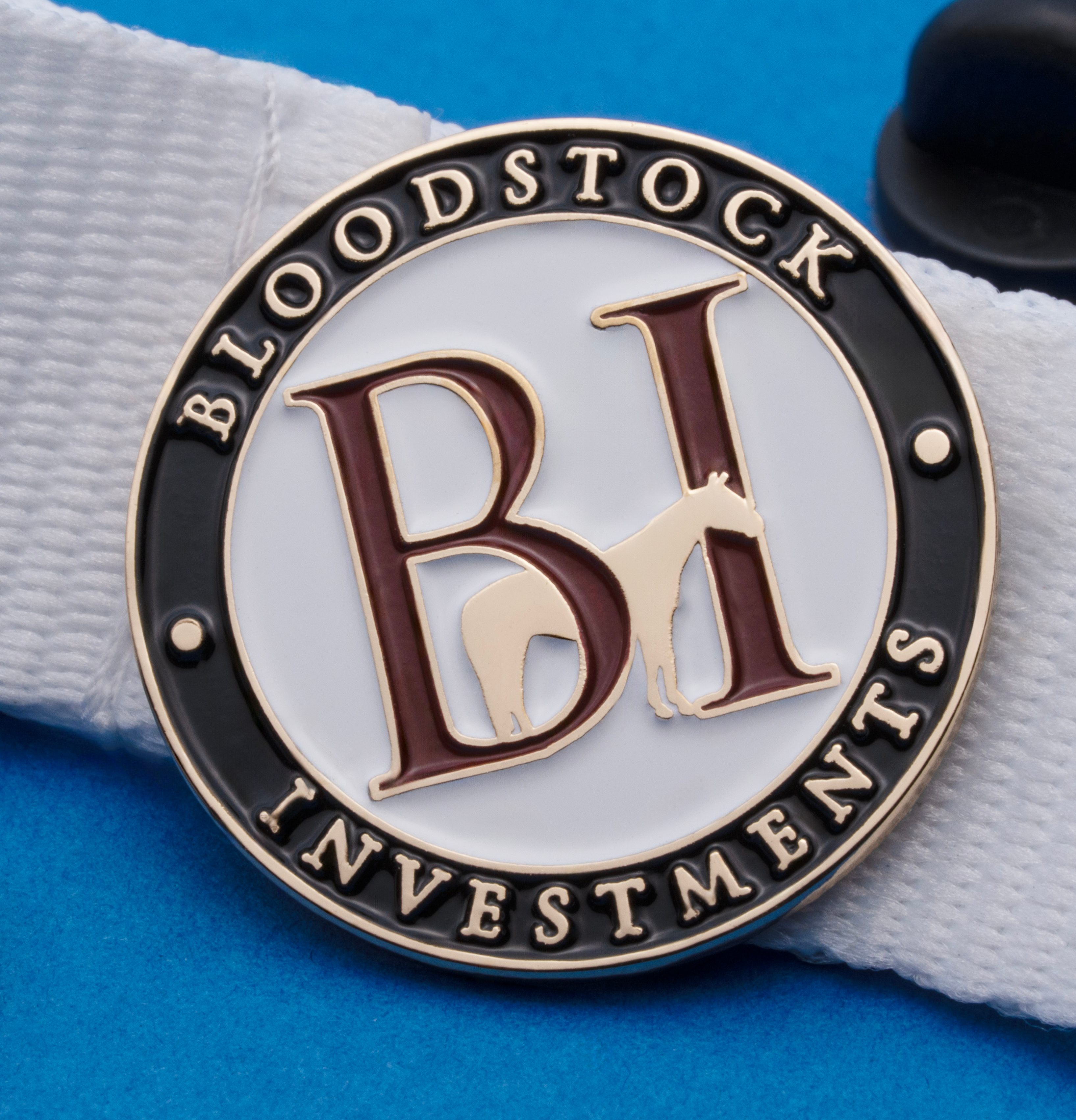 Circular enamel lapel pin for Bloodstock Investments featuring a horse silhouette and BI initials on a white strap.