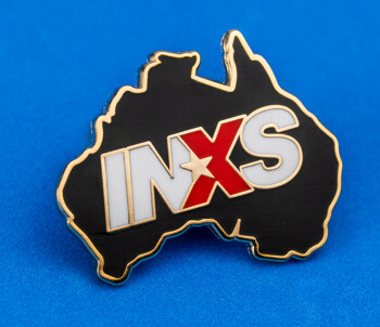Enamel lapel pin shaped like Australia with black background and INXS text in white and red.