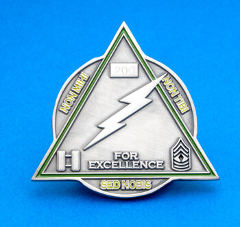 Triangular challenge coin with a lightning bolt, military rank insignias, and the text For Excellence.