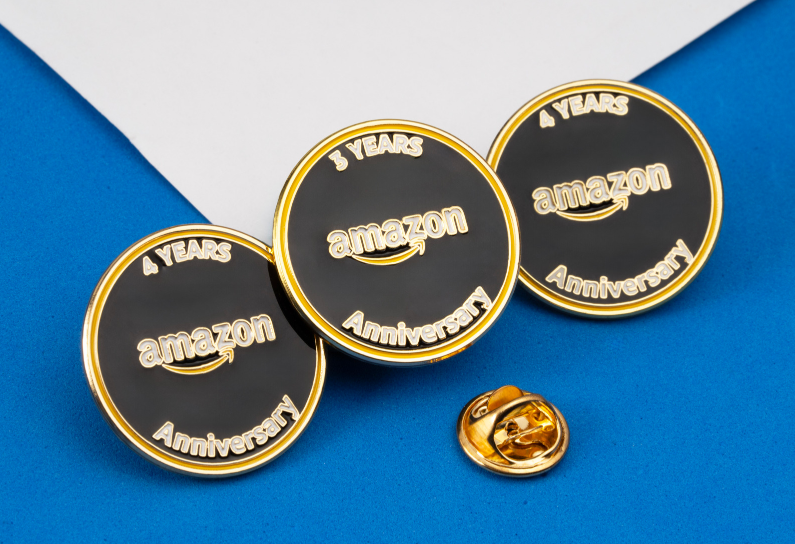 Circular black and gold Amazon Anniversary lapel pins for 3 and 4 years of service.
