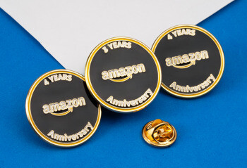 Circular black and gold Amazon Anniversary lapel pins for 3 and 4 years of service.