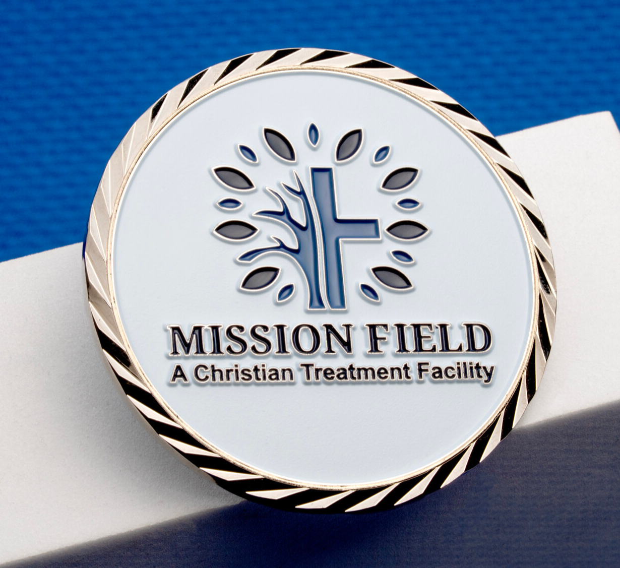Mission Field challenge coin featuring a tree and cross logo with a white enamel background and gold rope edge.