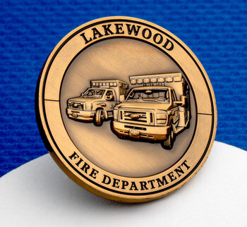 Antique brass challenge coin featuring Lakewood Fire Department ambulances on a blue background.