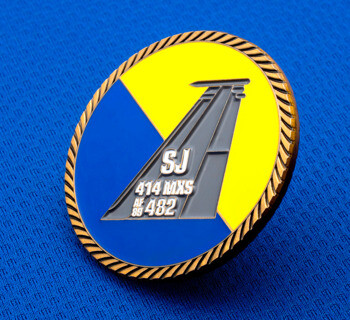 Circular challenge coin featuring a yellow and blue background with a grey aircraft tail fin and rope edge border.