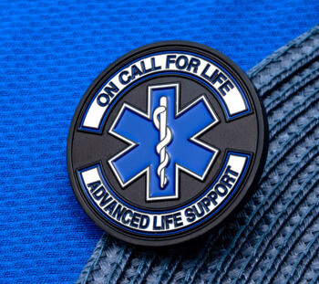 Circular PVC lapel pin featuring a blue Star of Life emblem with text reading On Call For Life and Advanced Life Support.