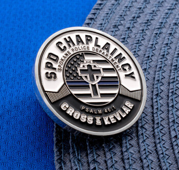 Circular lapel pin for SPD Chaplaincy featuring a cross over a thin blue line flag with Cross & Kevlar and Psalm 46:1 text.
