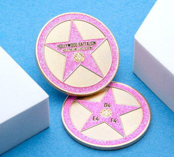 Hollywood Battalion challenge coin with pink glitter border, gold star design, and military seal on a blue background.
