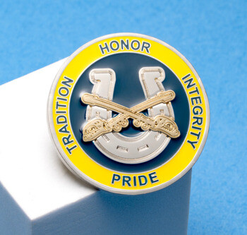Circular challenge coin featuring a silver horseshoe and crossed sabers on a blue and yellow background with the words Tradition, Honor, Integrity, and Pride.