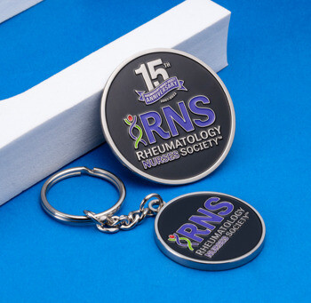 Rheumatology Nurses Society 15th Anniversary challenge coin and matching keychain with purple RNS logo on a black background.