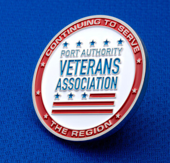 Port Authority Veterans Association challenge coin with red, white, and blue enamel, featuring stars and stripes on a blue fabric background.