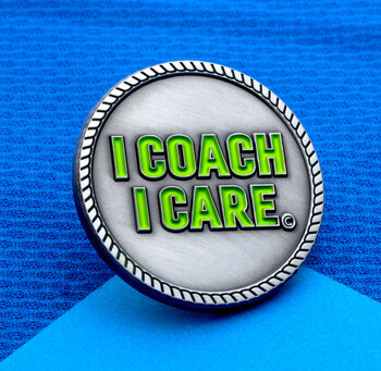 Circular silver lapel pin with a rope border featuring the text I COACH I CARE in green enamel letters.