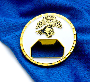 Gold and white circular bottle opener challenge coin featuring the Arizona Bobcats logo on a blue fabric background.