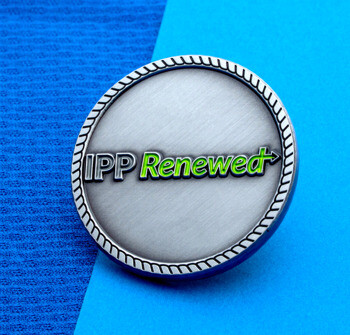 Antique silver challenge coin with IPP Renewed text in lime green and a rope border design.