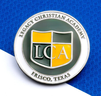 Circular Legacy Christian Academy lapel pin featuring a green and yellow LCA shield logo on a textured blue background.
