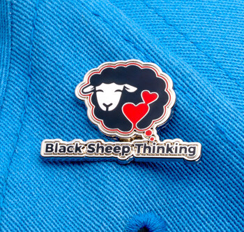 Custom lapel pin featuring the Black Sheep Thinking logo with a black sheep and red hearts inside a thought bubble, pinned to a blue cap.