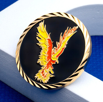 Custom challenge coin featuring a vibrant yellow, orange, and red phoenix emblem on a black enamel background with a gold rope-cut border.