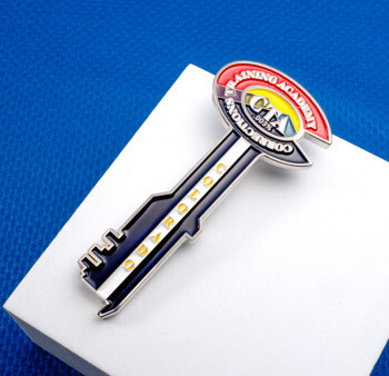 Custom key-shaped lapel pin featuring the Colorado Corrections Training Academy logo with red, yellow, and blue enamel colors.