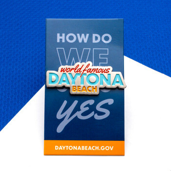 Custom World Famous Daytona Beach lapel pin mounted on a blue and orange backing card.