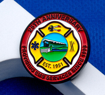 Circular EMS 25th Anniversary challenge coin featuring a yellow Maltese cross with a covered bridge illustration, Star of Life, and ladder on a blue background.