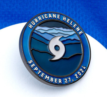 Circular Hurricane Helene September 27, 2024 challenge coin featuring a white hurricane symbol over blue mountain layers and a dark blue border.