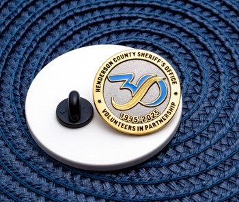 Henderson County Sheriff's Office Volunteers in Partnership 30th anniversary lapel pin with blue and gold numbers on a textured silver background.